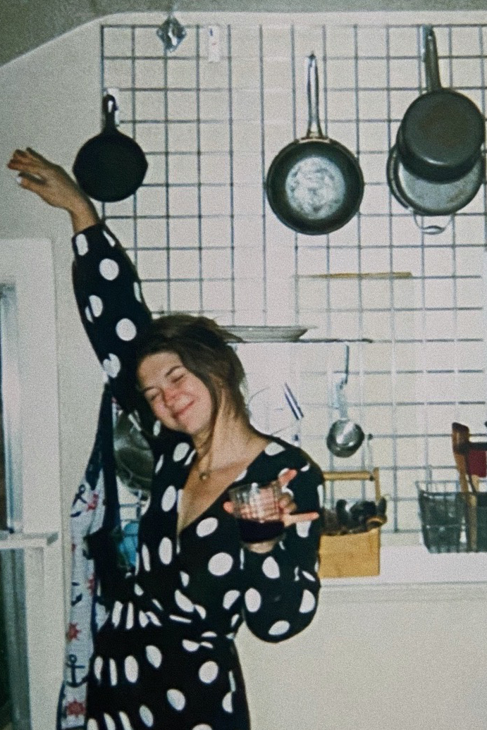 woman in polk-dot robe dances in kitchen
