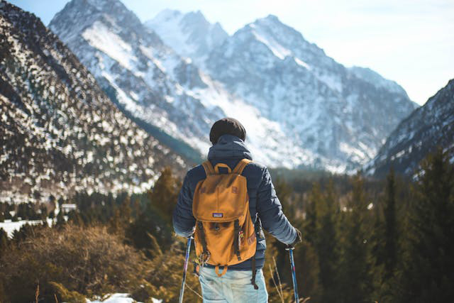 hiker with backpack viewing mountains in winter
